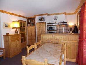 A kitchen with wooden cabinets, a dining table, and a microwave. - Spacious south-facing apartment - 6 guests (Pralognan-la-Vanoise)