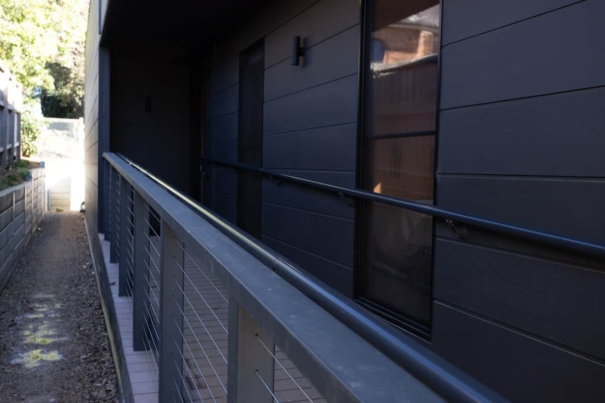 A modern building with a metal railing and a window with a dark blind.