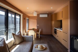 Espaço compacto com sofá, mesa de jantar e kitchenette.