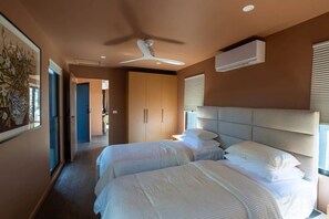 Quarto de hotel com cama, ventilador de teto, ar condicionado e quadro na parede.