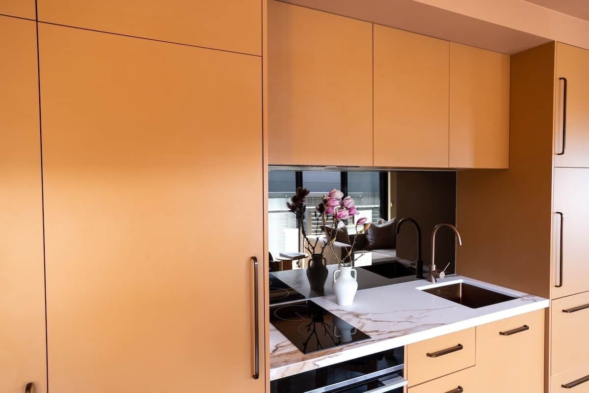 A modern kitchen with a marble countertop, a sink, and cabinets.