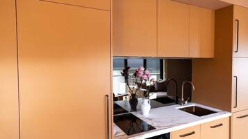A modern kitchen with a marble countertop, a sink, and cabinets.