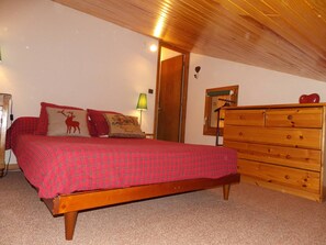 Quarto com cama, penteadeira, abajur e porta.