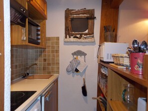 A kitchen with a microwave, oven, and various utensils on shelves. - Practical apartment 6 guests - Pralognan-la-Vanoise (Pralognan-la-Vanoise)