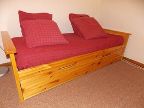A wooden bed with a red checkered bedspread and matching pillows. - Practical apartment 6 guests - Pralognan-la-Vanoise (Pralognan-la-Vanoise)