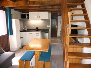 A compact kitchen with white cabinets, a microwave, and a coffee maker. There is a wooden table with benches and a wooden ladder in the background. - Mezzanine studio, pets allowed - 5 guests. Mountain view (Pralognan-la-Vanoise)