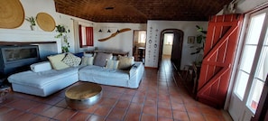 A living room with a sectional sofa, a coffee table, a television, and a red door.