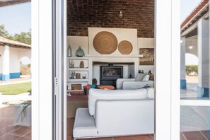 A modern living room with a white sofa, a fireplace, and decorative items on shelves. - Monte do Sobreiro: Sunny Days, Cozy Nights by the Fire, and the Comfort of Being Together (Évora)