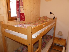 Ein Stockbett mit Blumenmuster, eine Nachttischlampe und ein kleiner Nachttisch aus Holz.