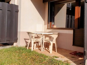 Eine kleine Terrasse mit Tisch und Stühlen, einem Holzzaun und einem Fenster.
