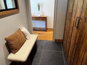 Ein Zimmer mit einer hölzernen Bank, einem kleinen Tisch mit einer Vase und einem Schrank mit Griffen.