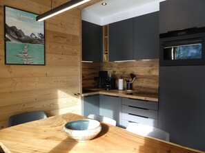 Eine moderne Küche mit Holzschränken, einem Holztisch und Blick auf eine Berglandschaft.
