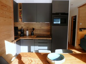 Eine kleine Küche mit integriertem Mikrowellenherd, einer Kaffeemaschine und einer Holz Arbeitsplatte.