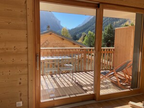 A wooden deck with a table and chairs, a view of mountains, and a wooden cabin. - Ideal apartment near slopes - 4 guests (Pralognan-la-Vanoise)
