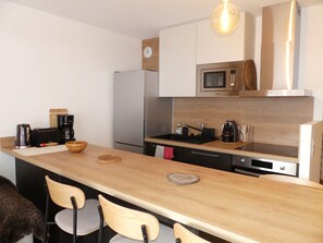Eine moderne Küche mit Holzarbeitsplatte, Edelstahlgeräten und einer eingebauten Mikrowelle.
