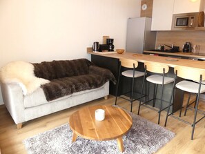 A compact living space with a sofa, a coffee table, a kitchen area with a microwave, and a bar stool. - Ideal apartment near slopes - 4 guests (Pralognan-la-Vanoise)