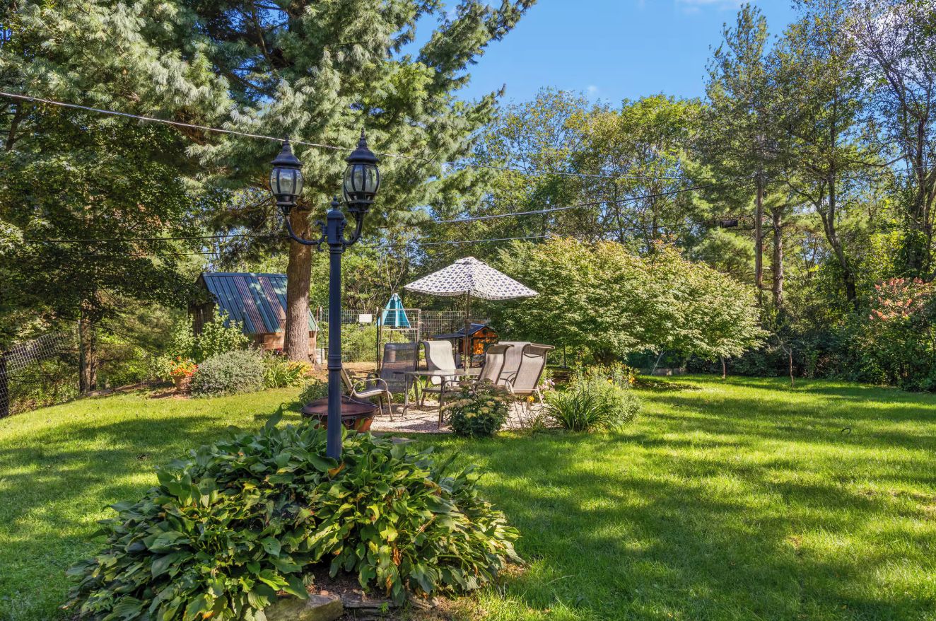 A well-maintained garden with a seating area, a lamp post, and a gazebo.