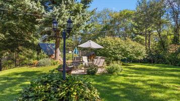 A well-maintained garden with a seating area, a lamp post, and a gazebo.