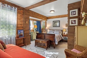 A cozy bedroom with a wooden bed, a dresser, a nightstand, and a wicker chair. - Charming Farm Cottage with Donkeys, Fire Pit, Wood Stove & Country Views (craryville)