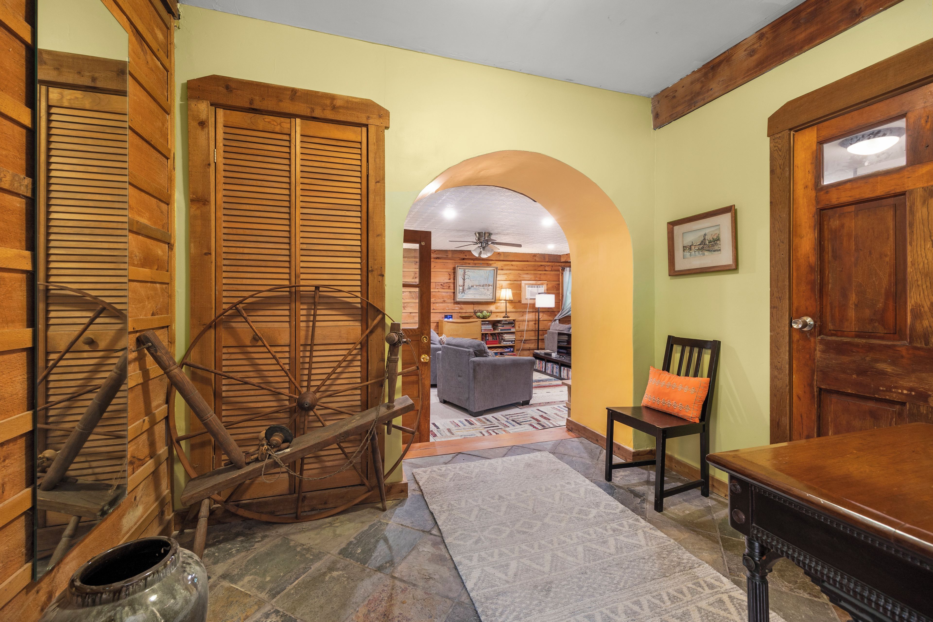 A room with wooden doors, a spinning wheel, a fireplace, and a cozy seating area.