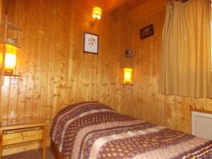 A wooden room with a bed, two wall-mounted lamps, a framed picture, and a window with curtains. - Perfectly located apartment - 4 guests (Pralognan-la-Vanoise)