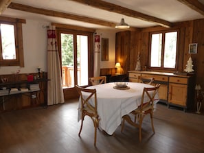 A dining area with a round table, wooden chairs, a chandelier, and a view through large windows. - Spacious chalet - 4 guests (Pralognan-la-Vanoise)