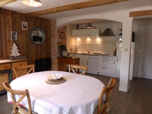 A cozy kitchen with wooden beams, a dining table with chairs, and a clock on the wall. - Spacious chalet - 4 guests (Pralognan-la-Vanoise)