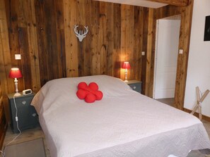A bedroom with a wooden wall, a bed with a white bedspread, two bedside tables with lamps, and a door. - Spacious chalet - 4 guests (Pralognan-la-Vanoise)