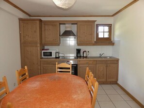 A compact kitchen with wooden cabinets, a microwave, a kettle, and a sink. - Cozy three-room near slopes - 6 guests (Pralognan-la-Vanoise)