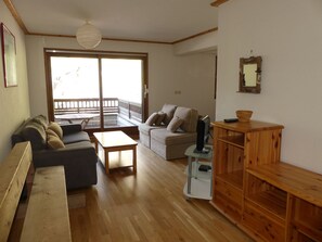 A living room with a sofa, a coffee table, a TV stand, and a wooden cabinet. - Cozy three-room near slopes - 6 guests (Pralognan-la-Vanoise)