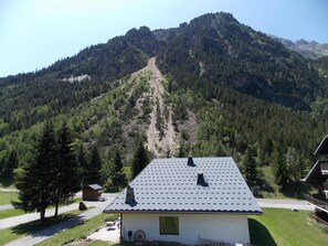 A mountain cabin with a sloped roof, surrounded by dense forest and a clear sky. - Duplex at the foot of the slopes - 4 guests (Pralognan-la-Vanoise)