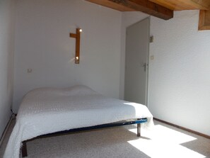 A bedroom with a single bed, a door, and a light fixture on the wall. - Duplex at the foot of the slopes - 4 guests (Pralognan-la-Vanoise)