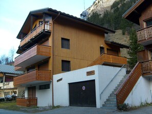 Ein mehrstöckiges Holzhaus mit Balkonen, einer Garage und einer Treppe, die zum Eingang führt.