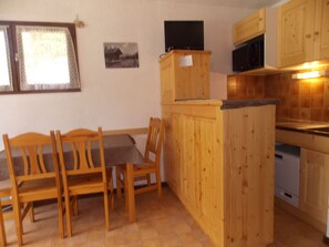 Ein Holzespeisesaal mit Stühlen, eine Küche mit Holzausstattung, einer Mikrowelle und einem Geschirrspüler.