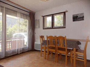 A dining area with a table and chairs, a window with curtains, and a picture on the wall. - Convenient studio near slopes - 4 guests (Pralognan-la-Vanoise)