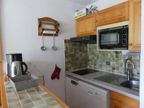 A kitchen with a microwave, stove, sink, and a dish rack. - Apartment in exclusive area - 4 guests (Pralognan-la-Vanoise)