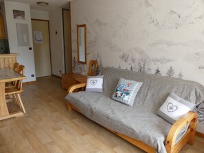 A living room with a sofa, two chairs, a wooden table, and a mirror. - Apartment in exclusive area - 4 guests (Pralognan-la-Vanoise)