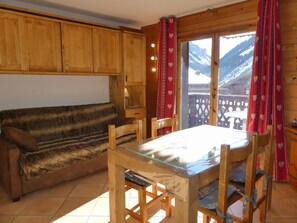 Ein gemütliches Zimmer mit einer Holzdavonia, einem Glastisch und Sesseln.