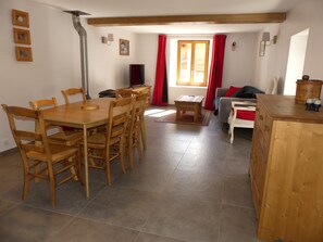 Ein Essbereich mit einem Holztisch und Stühlen, einem kleinen Holztisch und einer Couch mit roten Kissen.