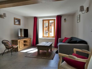 A living room with a television, wooden furniture, a sofa, and a window with curtains. - Renovated house at the slopes - 5 guests (Pralognan-la-Vanoise)