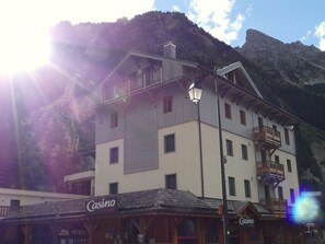A multi-story building with balconies, a casino sign, and a mountain backdrop. - Apartment with terrace - 6 guests (Pralognan-la-Vanoise)