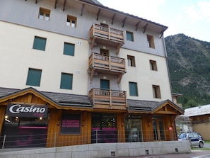 A multi-story building with balconies, a casino shop, and a mountain backdrop. - Apartment with terrace - 6 guests (Pralognan-la-Vanoise)