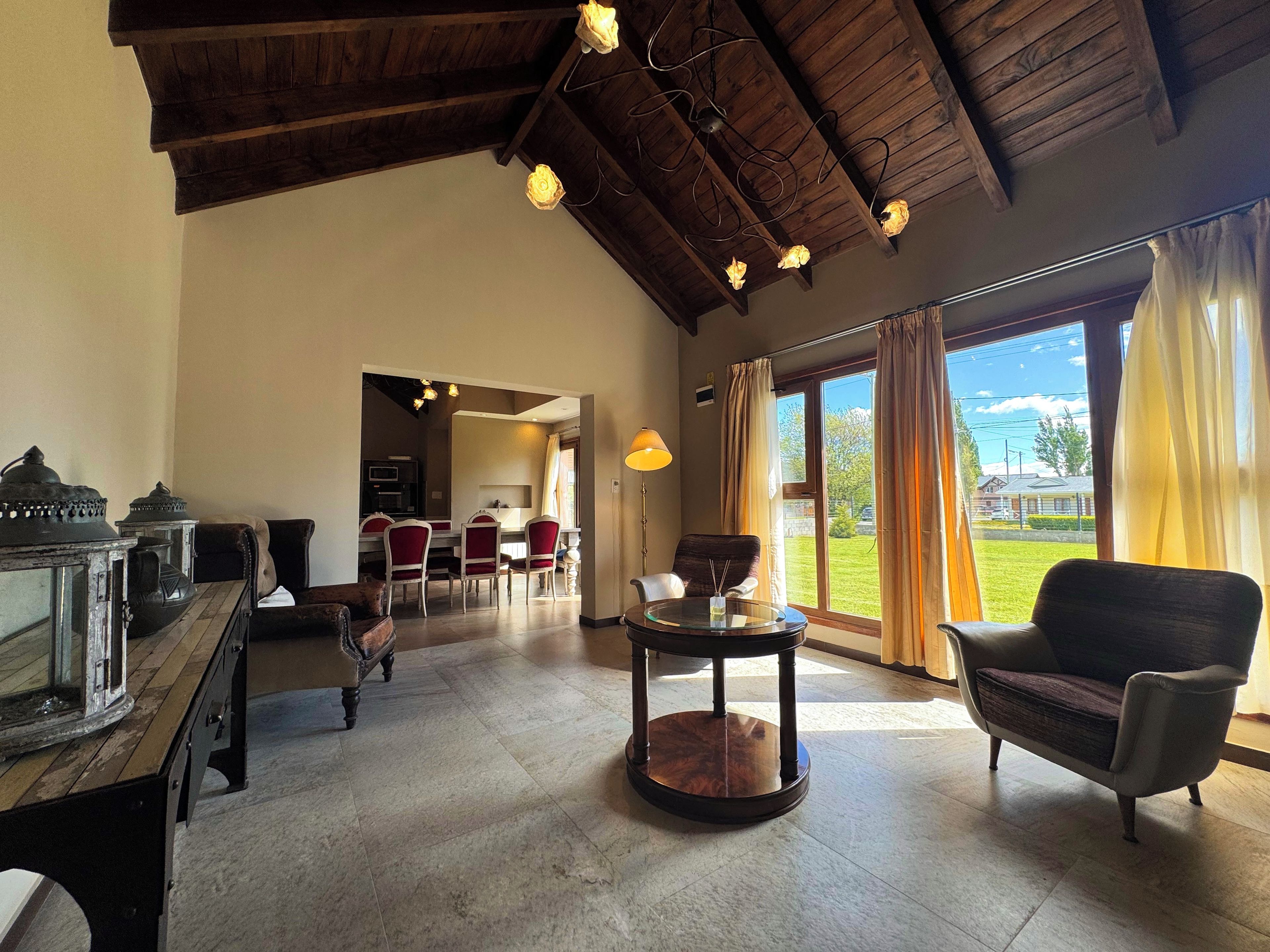 Un espacio amplio con techo alto, zona de comedor y vistas al exterior.