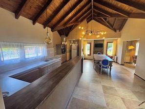 A spacious kitchen with a large island, wooden ceiling beams, and pendant lighting.