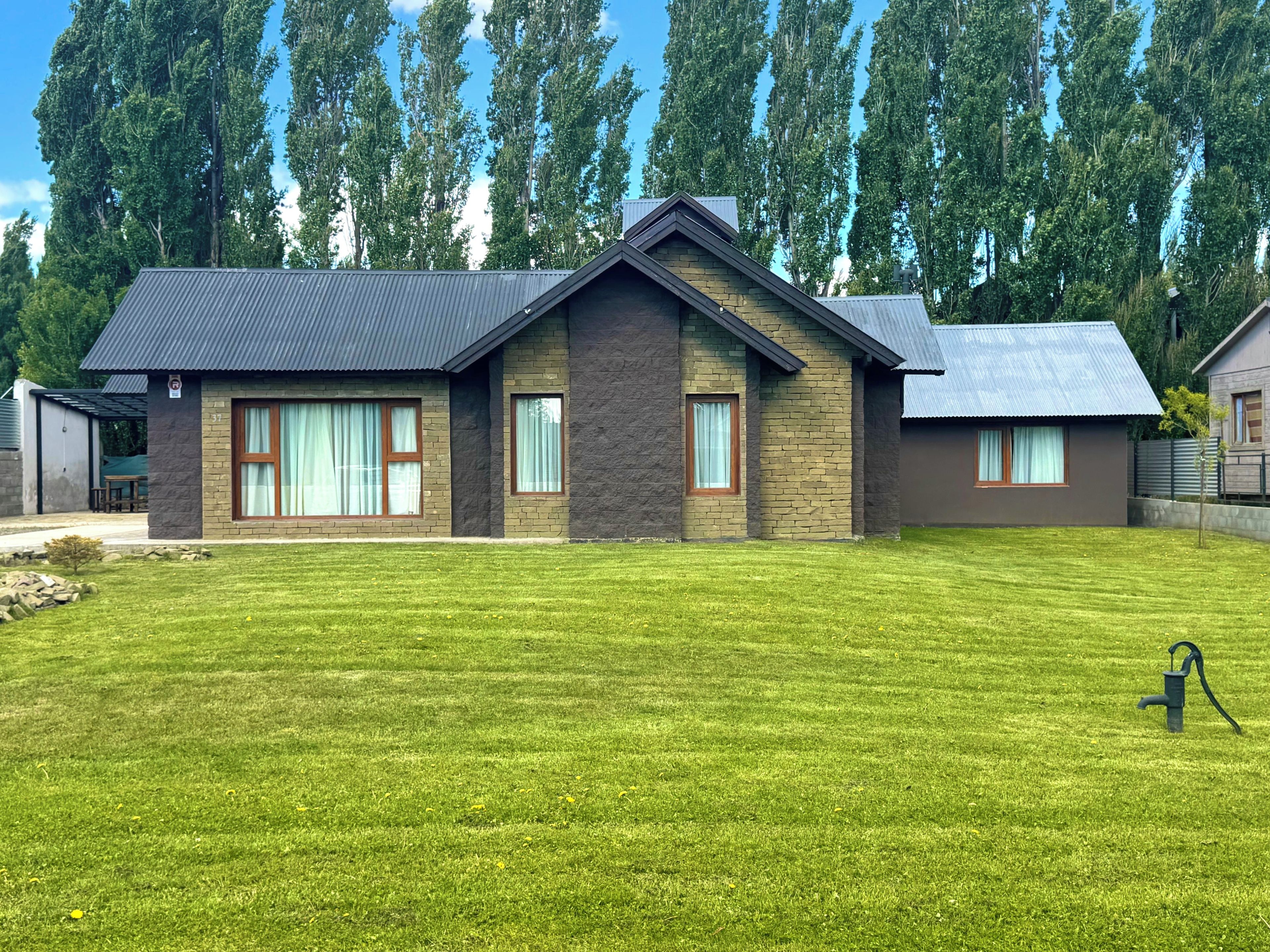 A two-story house with a sloped roof, large windows, and a well-maintained lawn.