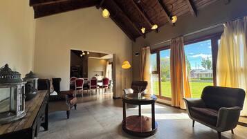 A spacious room with a high ceiling, a dining area, and a view of the outdoors.