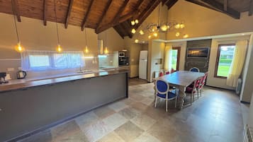 A modern kitchen with a central island, a dining area with a table and chairs, and a view of the outdoors through a window.