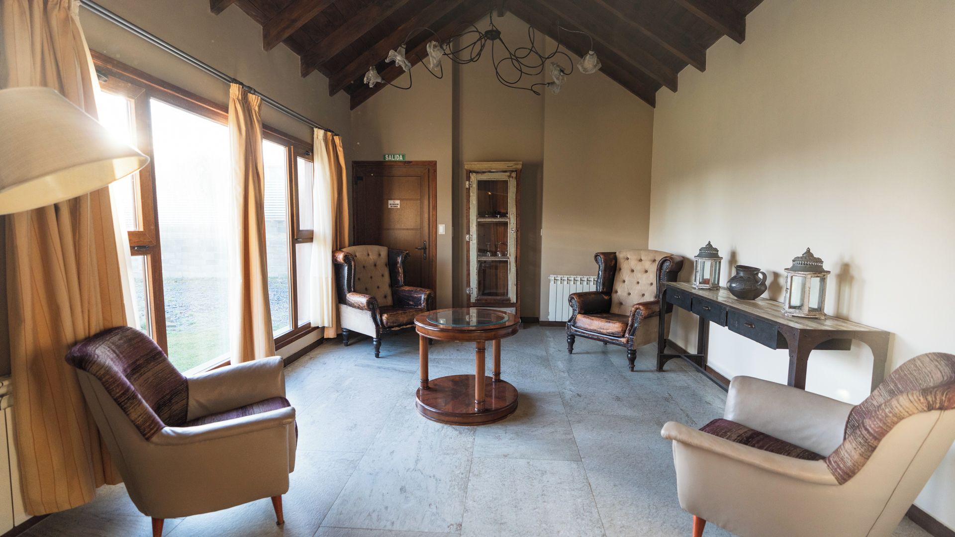 Una habitación con chimenea, una mesa redonda y dos sillones.