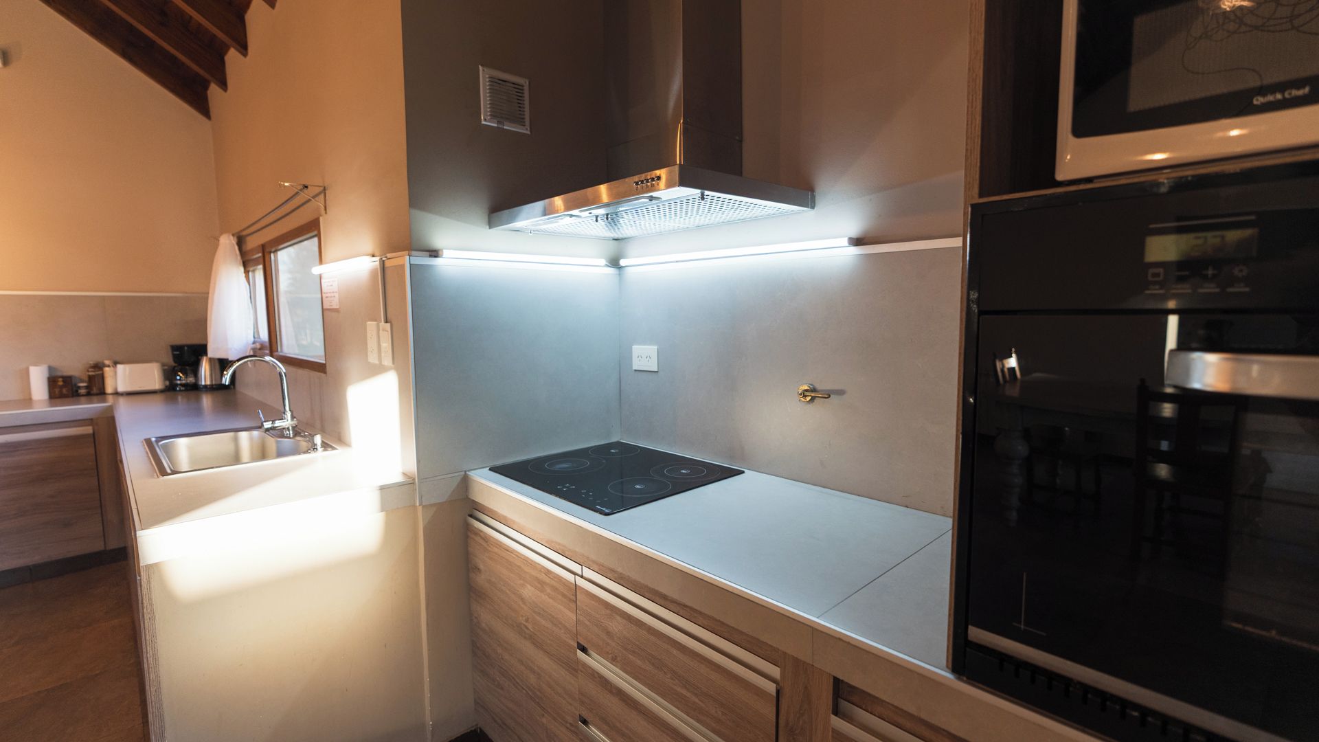 Una cocina moderna con estufa integrada, microondas y pileta de acero inoxidable.