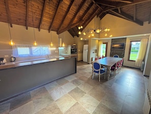 Cozinha moderna com ilha central, área de jantar com mesa e cadeiras, e vista para o exterior por uma janela.